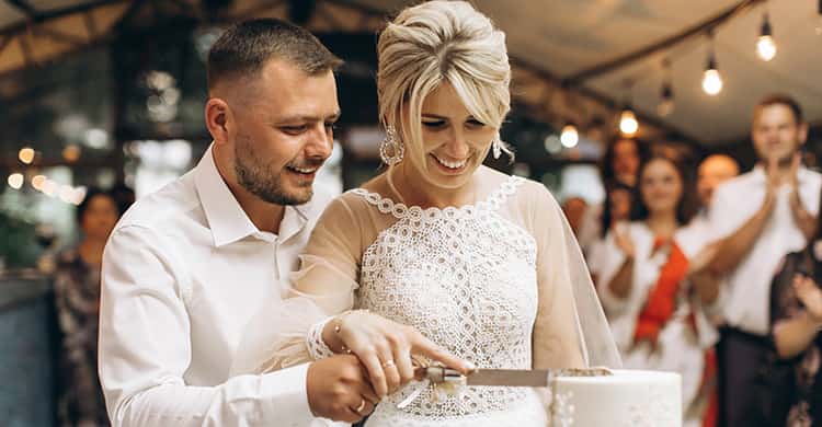 A bride and groom smile at each other while guests cheer